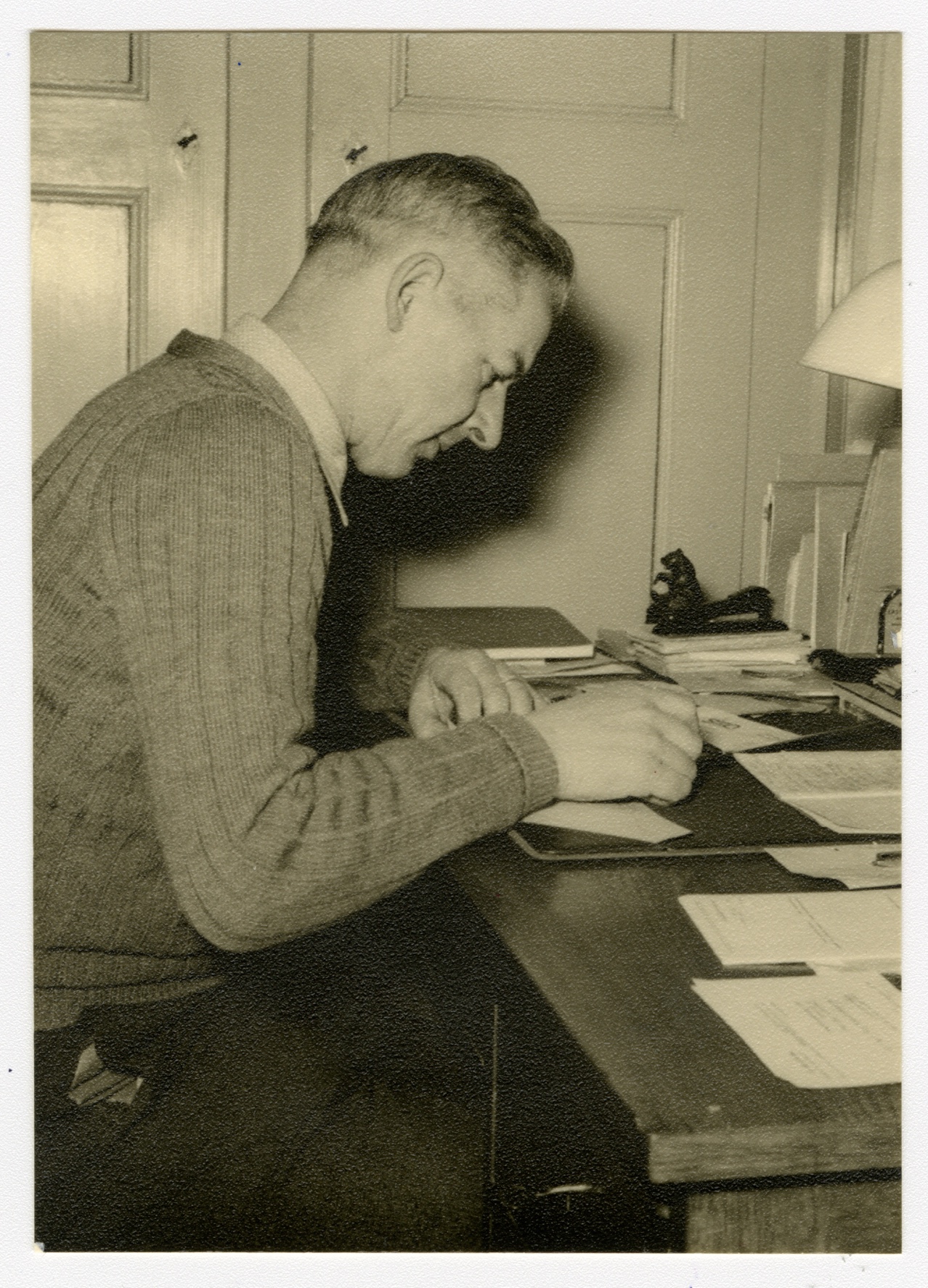 Alte schwarz-weiss Fotografie, auf der ein Mann mittleren Alters, Hans Weiss, abgebildet ist, der am Schreibtisch arbeitet.